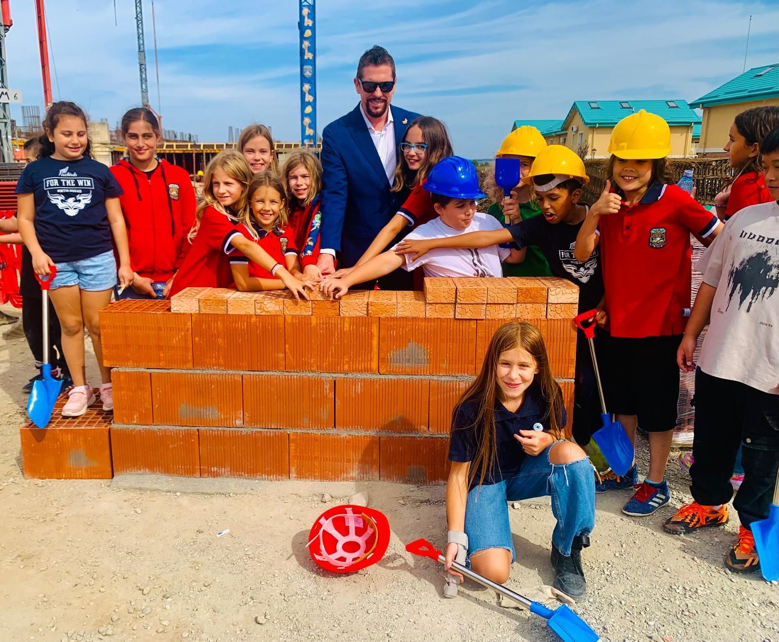 Dr. Wilkens with students laying bricks at the new campus construction site