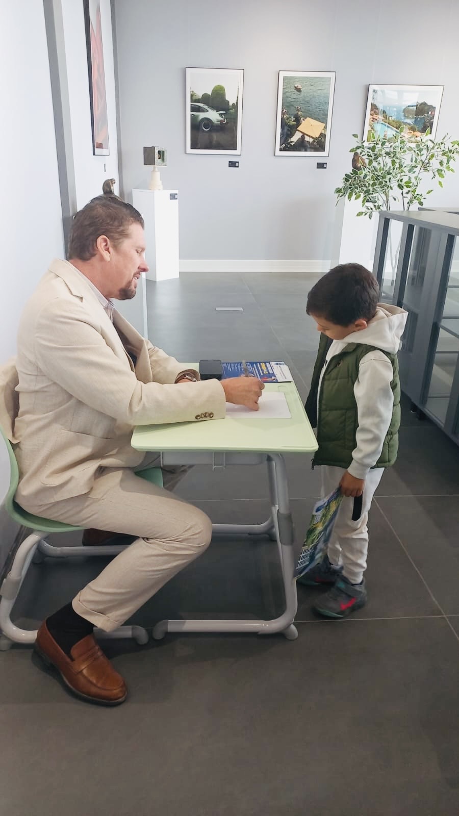Dr. Wilkens kneeling at a small desk for a one-on-one check-in with a young learner
