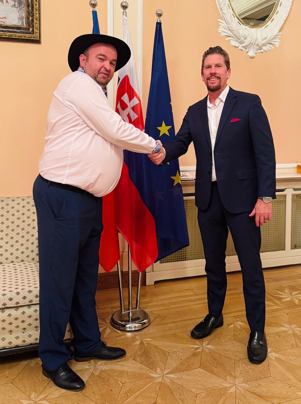 Dr. Wilkens shaking hands with a Slovakian diplomat beside Slovakian and EU flags