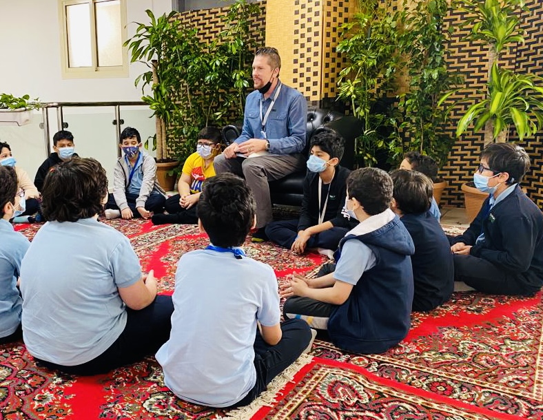 Dr. Wilkens seated in a circle with students on a patterned rug for discussion